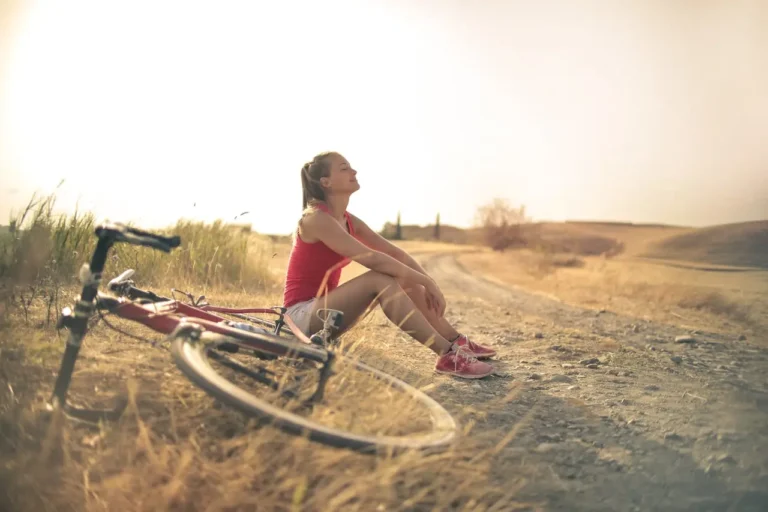 Frau sitzt neben ihrem Fahrrad in der Sonne